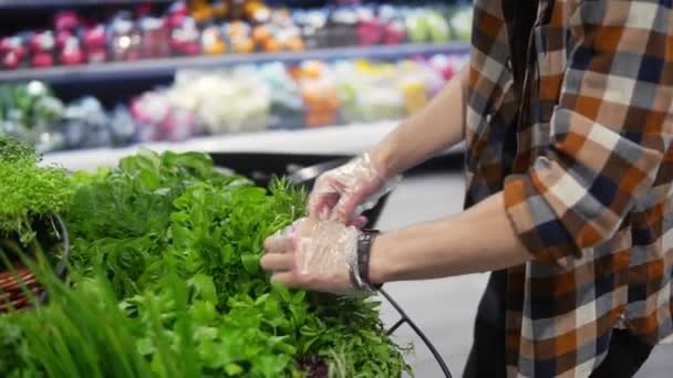 Koruyucu siyah maskeli genç bir adam süpermarkette yürüyor ve raftan yeşillikleri alıyor. Corona Virüsü fikri — Stok video