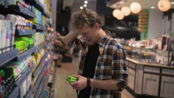 Kaukasisk ung man med feminina kuddar i gallerian och läsa etiketten, grimma. Begreppet shopping och val. Sidovy — Stockvideo