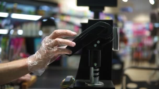 Süpermarket: kasayı kontrol et. Müşteri yemek malzemeleri için akıllı telefonla ödeme yapıyor. Cep telefonunu kablosuz terminale uyguluyor. Yüzler yok. Kapat. — Stok video