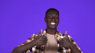 Mutlu, gülümseyen Afrikalı Amerikalı adam mavi arka planda iyi bir ruh hali içinde. El kol hareketi, jest gibi - insani duygular.