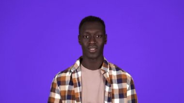 Mavi arka planda izole edilmiş Afro-Amerikan bir adam havayla öpüşen kameraya bakıyor. Güzel ve mutlu. Aşk ifadesi