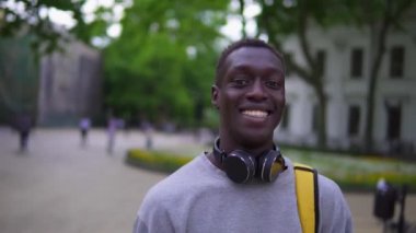 Yakışıklı, Afro-Amerikalı genç bir adamın portresi. Kameraya gülümseyen ve gezici hayat tarzıyla sakin bir şehir akşamının tadını çıkaran. Bulanık arkaplan