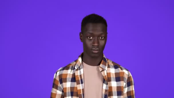 Schöner afrikanisch-amerikanischer Typ in stylischem kariertem Hemd, Tempel anfassen und dann Kamera zeigen, nachdenken, überlegen, handeln und Gehirn einsetzen, blauer Hintergrund — Stockvideo