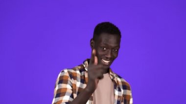 Neşeli Afro-Amerikalı adam bana jest yapıyor. Partide tanışıyor ya da flört ediyor. Mavi arkaplan üzerinde izole edilmiş