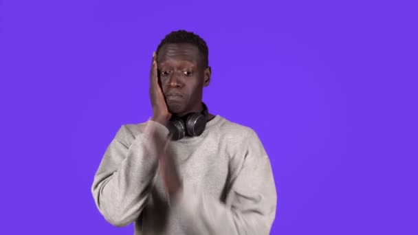 Retrato de un joven guapo con camisa blanca y auriculares en el cuello: súper sorprendido y sorprendido con los ojos y la boca bien abiertos, rostro conmovedor, aislado sobre fondo azul. Emociones humanas — Vídeos de Stock