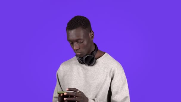 Portrait of handsome young man shocked surprise, mad by what he sees on his cell phone screen, close his his face with emotions, isolated on blue background. Negative human emotion facial — Stock Video