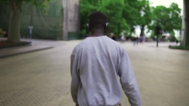 Sıradan dans eden, kulaklıkla gezen, şehirde tek başına eğlenen, gülümseyen, kaygısız neşeli Afrikalı Amerikalı adam. Gençlik ve eğlence konsepti. Nadir görünüm