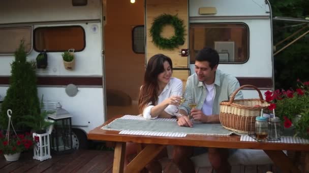 Portrait de couple européen mignon homme et femme buvant du vin blanc assis ensemble à la table en bois à l'extérieur. Élégant, statique roues maison sur fond — Video