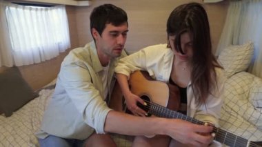 Beyaz, siyah saçlı genç adam kız arkadaşına gitar çalmayı öğretiyor. Tekerlekli sandalyede, karavanda oturuyor. Birbirine aşık romantik bir çift yatakta oturmuş, akorları tekrarlıyorlar. Kapat.