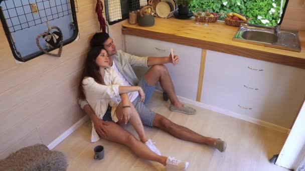 Beautiful couple sitting on the floor in the stylish kitchen in van and doing selfie using smartphone, posing. Наслаждаемся общением, совместными праздниками, путешествиями на колесах. Современный интерьер. Высокий — стоковое видео