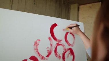 Tanınmayan kadın ressamların yakın çekimleri tuvale kırmızı şakayık ya da diğer çiçekleri boyar. Sanatçı, tuvale pembe çiçekler çizer. Kalın bir fırça ile, yakın plan.