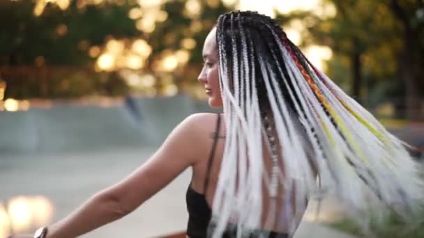 Joven chica hermosa con rastas bailando en un parque. Hermosa mujer en pantalones beige y top negro escuchando música en su mente y bailando durante un día soleado. Disparo en cámara lenta — Vídeos de Stock