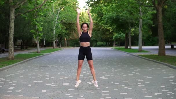 Full length footage of athletic stylish sportswoman doing crossfit bounce jumps and squats. Girl wearing black tight sportswear and sneakers. Slow motion — Stock Video