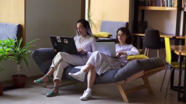 İki dizüstü bilgisayar kullanan ciddi konsantre kadın serbest çalışanlar. Evden ya da kamu işyerinden online olarak çalışan Kafkas zarif kadınların portresi. Serbest konsept, yaşam tarzı, güven