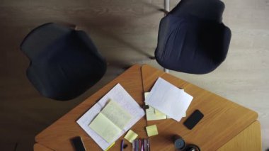 Tanımlanamayan iki kadın gelip sandalyeye oturuyor ve not defterine notlar yazmaya başlıyorlar. İş fikirlerini yazıyorum. İki iş kadınının el yazısı notları. Beyaz bluzlu kadınlar.