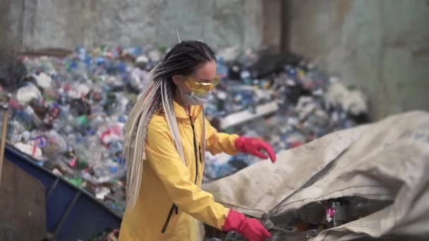 Žena-dobrovolnice ve žlutém a průhledném ochranném skle třídění použitých plastových lahví v moderním recyklačním závodě. Oddělená sbírka odpadků. Třídění koše — Stock video