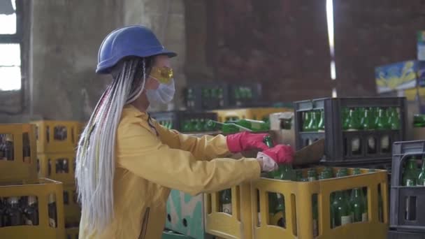 Kvinnliga arbetstagare kontrollerar återvinningen av avfall separering av återvinningsbara avfallsanläggningar. Sortera glasflaskor i kartonger för vidare destruktion. Sidovy — Stockvideo