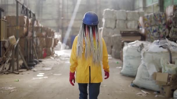 쓰레기 처리 공장. 더 많은 처리를 위해 쓰레기를 재활용하고 저장 한다. 딱딱 한 모자를 쓰고 일하는 여자가 압축 된 쓰레기 더미를 걷고 있습니다. 거대 한 더미들 이죠. 희귀 한 견 해 — 비디오