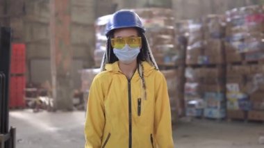 Atık işleme tesisi. Daha fazla atık için geri dönüşüm ve depolama. Sert şapkalı, eldivenli ve maskeli kadın atık yığınları arasında yürüyor, kocaman kazıklar. Ön görünüm