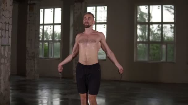 Fit shirtless sportsman είναι skipping με σχοινάκι άλμα στο στούντιο γυμναστήριο επικεντρώθηκε στην άσκηση καρδιο φορώντας μαύρο σορτς. Άσκηση, οι άνθρωποι και την έννοια της αθλητικής κατάρτισης. Αργή κίνηση — Αρχείο Βίντεο