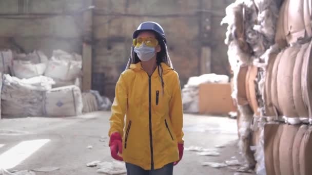 廃棄物処理工場。廃棄物の再資源化と貯蔵。女性労働者のハード帽子、手袋、マスクを押し廃棄物のスタックを歩くと、巨大な杭。正面図 — ストック動画