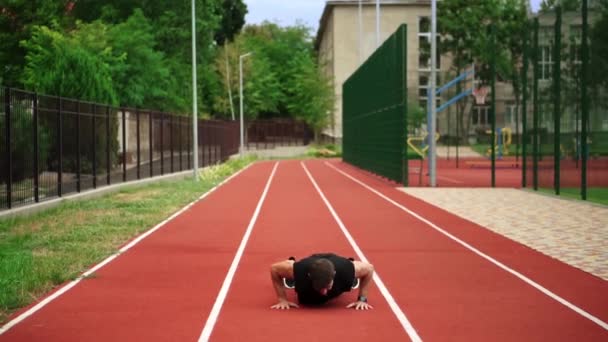 Fit, vousatý muž stojící na běžecké trati venku na moderním stadionu dělá cvičení — Stock video