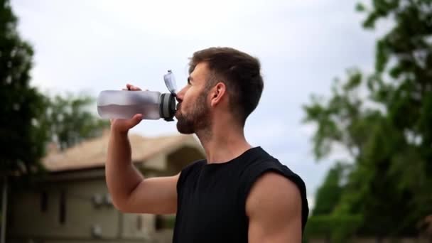 Portret van dorstige sportman die mineraalwater drinkt na outdoor training — Stockvideo
