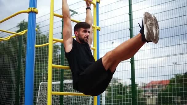 Atletische sporter traint kernspieren met beenlift op verticaal ladderrek op een outdoor fitnesscentrum — Stockvideo