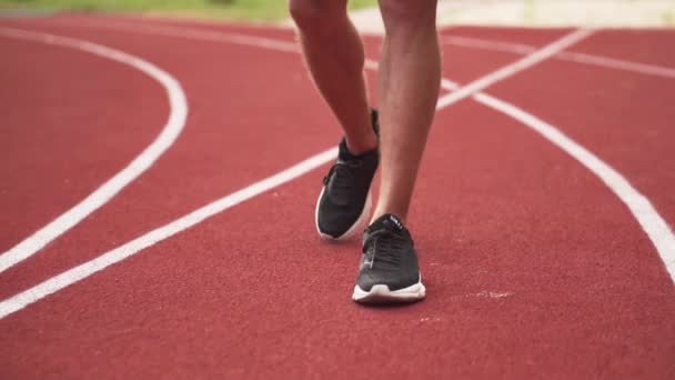一名身穿黑色运动鞋的男子的腿在室外赛马场上与体重增加一起在慢速跑道上训练的镜头 — 图库视频影像