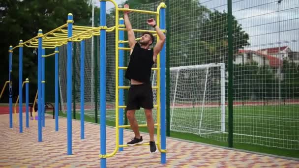 Man training kernspieren met beenlift op verticale ladder rek op een outdoor fitnesscentrum — Stockvideo