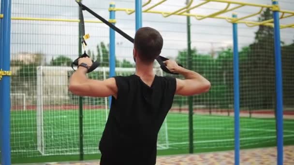 Egy atlétikai ember gyakorolja gumi öv segítségével, hogy erőltesse strenth edzés mellizom és bicepsz — Stock videók