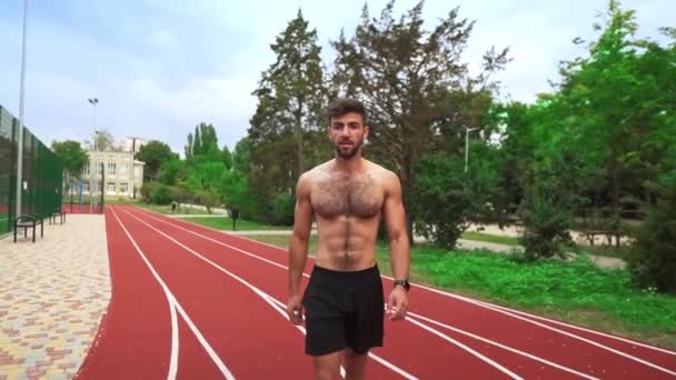 Retrato de um homem cansado, sem camisa indo em corrida de estádio após o treinamento duro — Vídeo de Stock