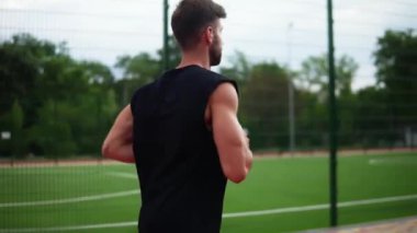 Atletizm stadyumunda siyah gömlekli bir sporcunun yan görüntüsü