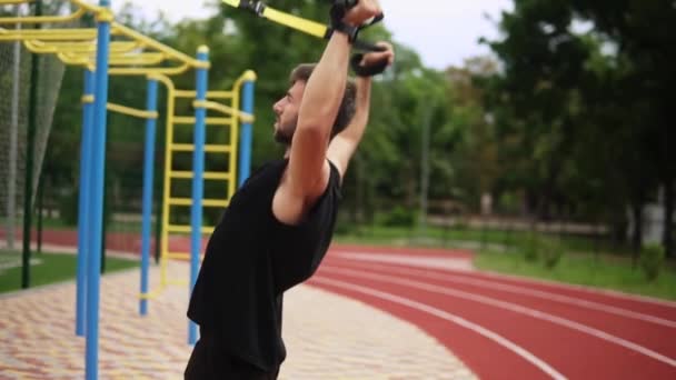 Een atletische man doet biceps oefening met behulp van rubberen riem om 10 / 10 van de training buiten te dwingen — Stockvideo