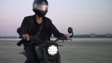 Konsantre motorcular siyah spor bisiklete biniyor ve ön farlarını değiştiriyor. Akşam alacakaranlığı