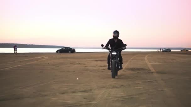 Vista frontal do jovem motociclista em capacete e jaqueta, o homem está andando de moto esporte. Vento soprando, frente de água — Vídeo de Stock