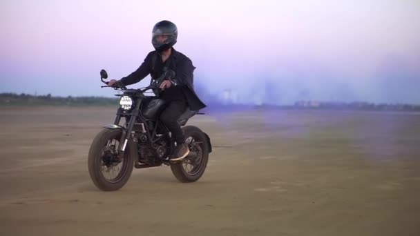 Young biker in black riding while the engine blowing out blue exhaust smoke, holi — Stock Video