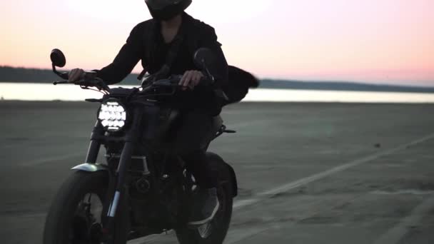 Motociclista su bici sportiva nera in casco con fanale anteriore commutato da terreno sporco e sabbioso — Video Stock