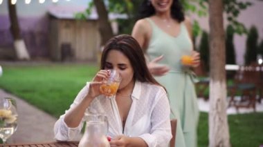 Uzun saçlı kadın kafede kız arkadaşını bekliyor. Gelip onu öpüyor ve sarılıyor.