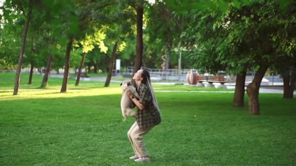 女の子と豚の犬は楽しんでいる、彼女は公園で空気中の犬を投げます — ストック動画