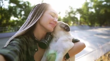 Tatlı bir bej köpek yavrusu yüzünü yalamaya çalışıyor. Bir kadın kamerayı ve şaşıları tutuyor.