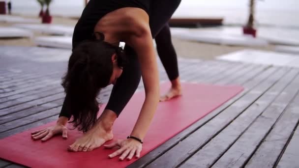 Femme mince faisant du yoga ou s'étirant sur le tapis à l'extérieur - torse penché vers l'avant - pose pyramidale — Video