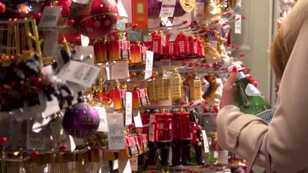 Женщина выбирает рождественские игрушки для украшения ёлки. Крупный план. Универмаг Свободы. Лондон, Великобритания — стоковое видео