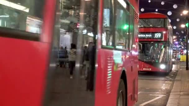 Vánoční osvětlení, červené autobusy a černé taxíky na rušnou ulici Oxford. Londýn, Velká Británie — Stock video