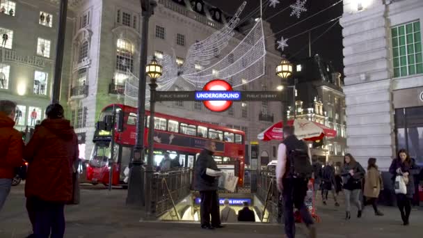 Ludzie są w pośpiechu do stacji metra Piccadilly Circus w godzinach szczytu rozpoczynają się, gdy dystrybutorzy gazety rozpowszechniać bezpłatną gazetę. London, Wielka Brytania — Wideo stockowe