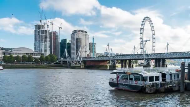 Солнечный день паромы проходят Хангерфорд мост с London Eye и Royal Festival Hall в фоновом режиме. Время истекло. Лондон, Англия — стоковое видео