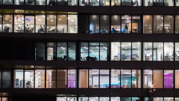 사람들은 밤에 사무실 건물에서 일합니다. 사무실 창에 대한 닫기 보기. — 비디오