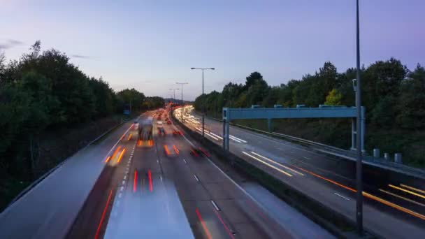 Vista de lapso de tiempo de una autopista ocupada con senderos de luz durante una puesta de sol . — Vídeos de Stock