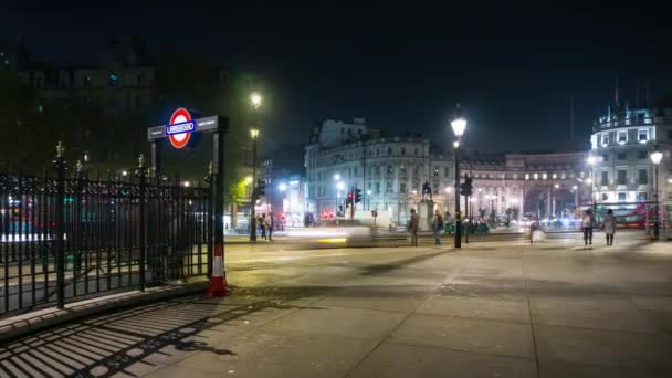 Trafalgar Square y la entrada al pasaje subterráneo Charing Cross estación de metro en la noche. Tráfico, autobuses rojos, taxis negros y gente ocupada . — Vídeos de Stock