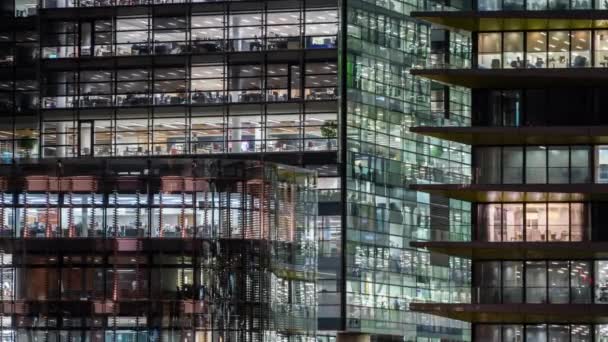 Fenster des mehrstöckigen Gebäudes aus Glas und Stahl Bürobeleuchtung und arbeitende Menschen in — Stockvideo